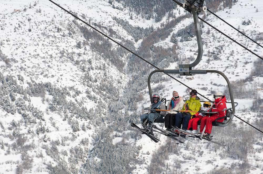 Vier Skifahrer in einem Sessellift in Serre Chevalier