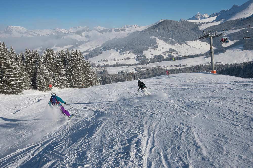 Zwei Skifahrer auf der Piste mit Sessellift