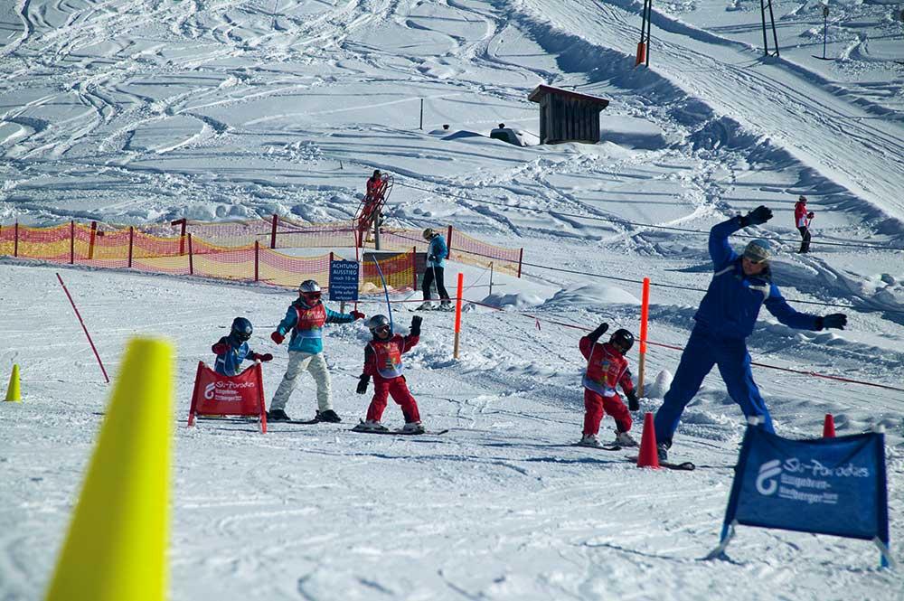 Skilehrer mit Kindernbeim Slalomfahren in der Skischule Grasgehren