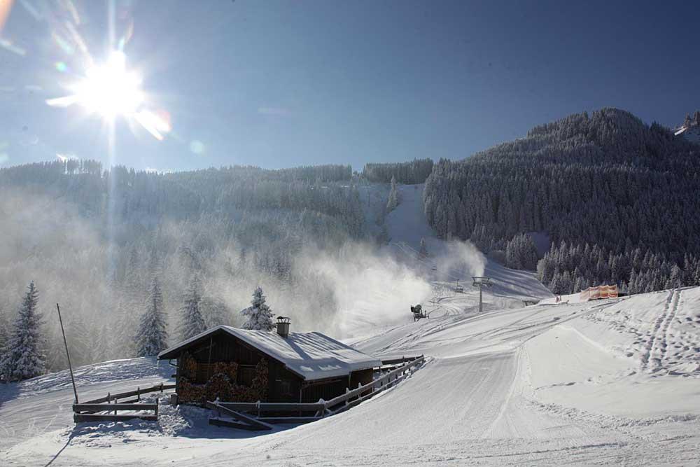 Blick auf Hütte und Schneekanone im verschneiten Skigebiet Alpspitzbahn Nesselwang