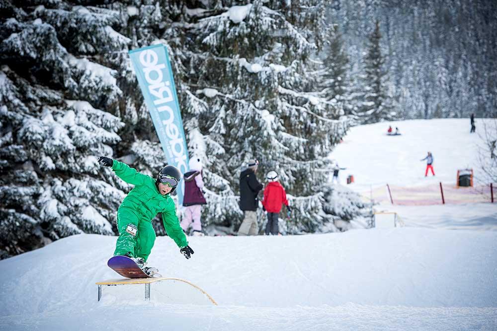 Kind mit Snowboard grindet über Rail im Kidspark Nesselwang