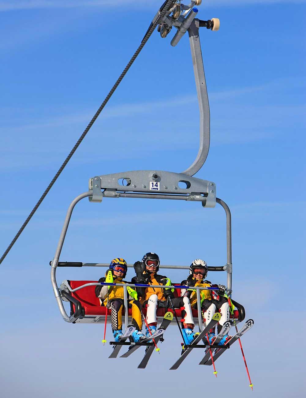 Drei Skifahrer im Sessellift Nesselwang