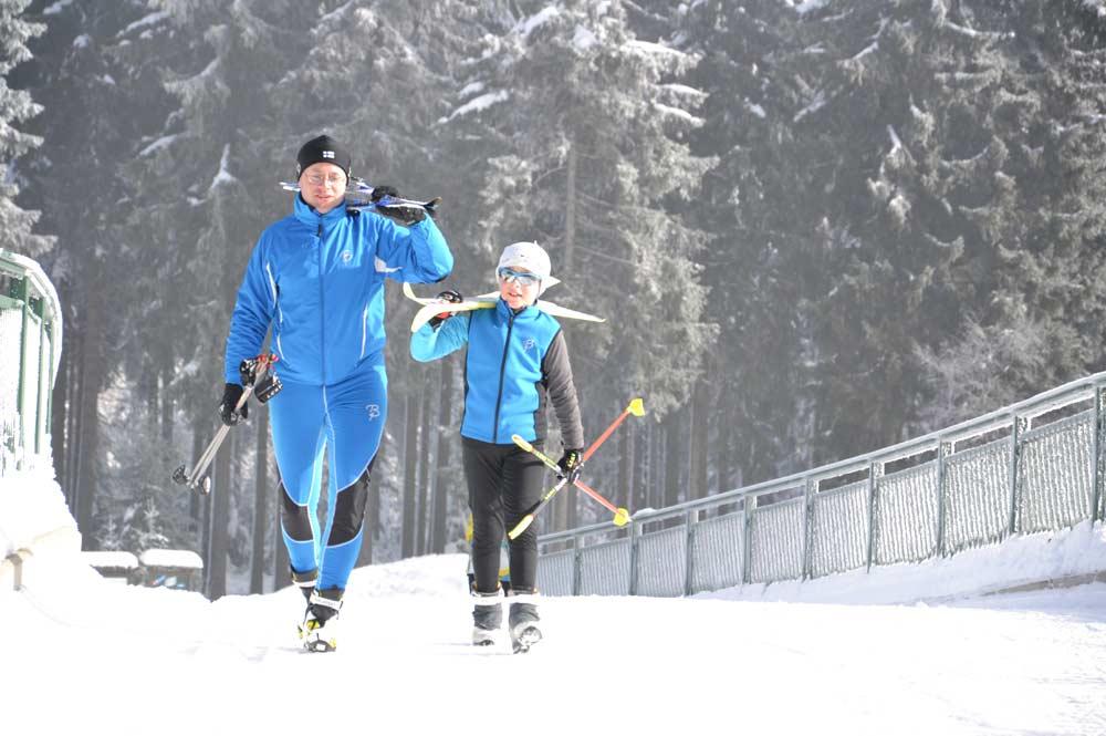 Vater und Sohn mit Ski auf den Schultern in Klingenthal