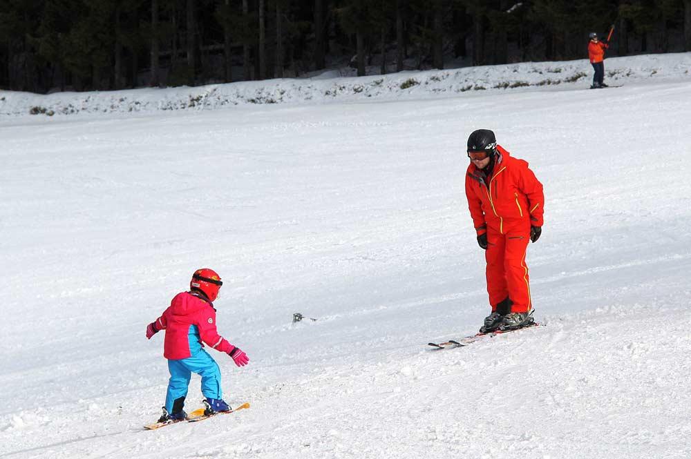 Vater mit Kind auf der Piste im Skigebiet Kreuzberg