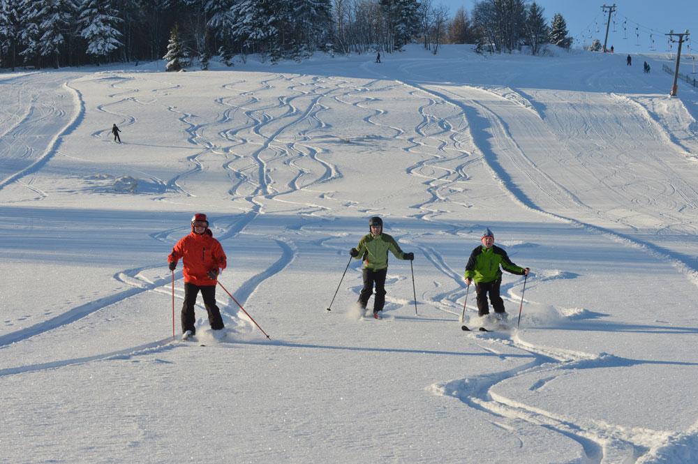 Drei Skifahrer auf der Tiefschneepiste in Geising