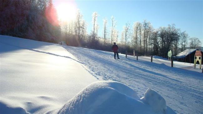 Skifahrer auf Piste mit Neuschnee bei Sonnenuntergang
