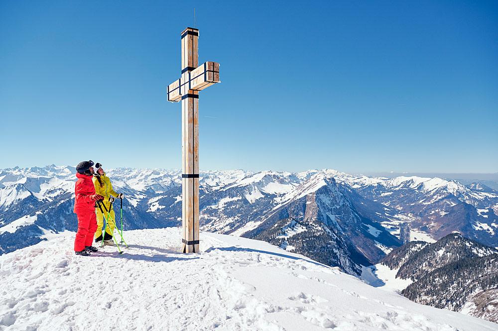Skifahrer an einem Gipfelkreuz im Skigebiet Diedamskopf