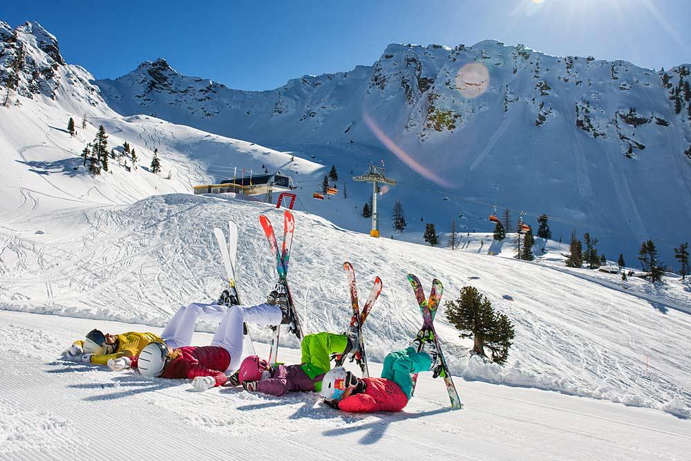 Skifahrer kreuzen ihre Ski vor dem Bergpanorama am Hauser Kaibling