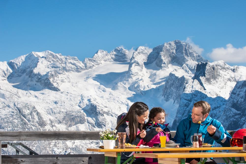 Familie beim Essen auf der Sonnenterrasse im Skigebiet Dachstein West