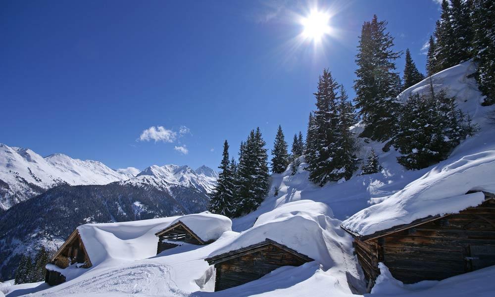 Verschneite Hütten bei Sonnenschein