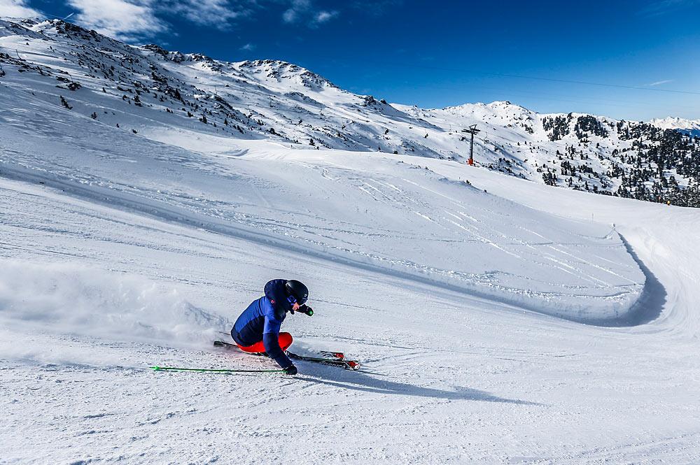 Skifahrer bei der Abfahrt auf einer breiten Piste am Glungezer