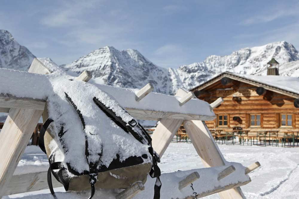 Rucksack am Skiständer vor einer Hütte