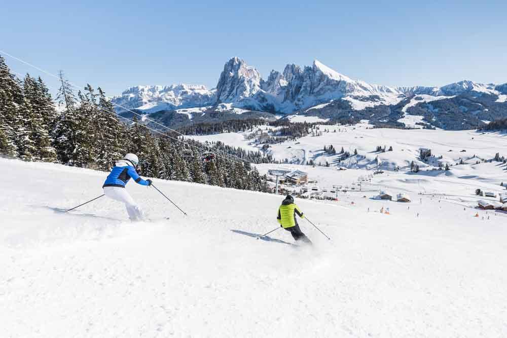 Zwei Skifahrer fahren die Piste auf der Seiser Alm herunter