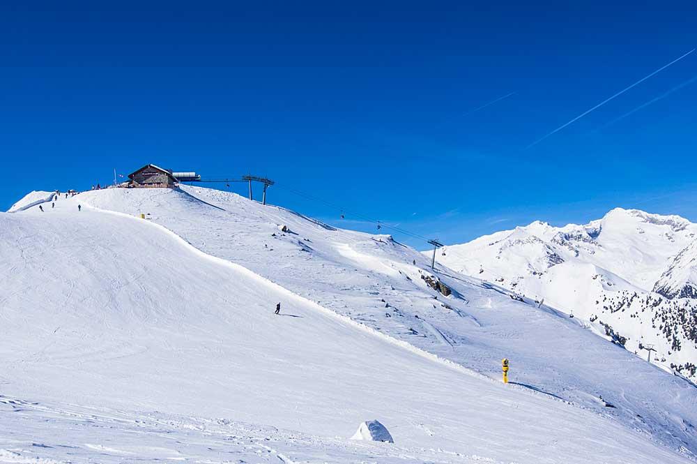 Skifahrer auf Piste am Speikboden mit Hütte im Hintergrund