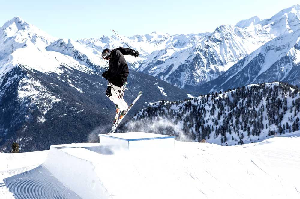 Skifahrer springt über Kicker im Snowpark Speikboden