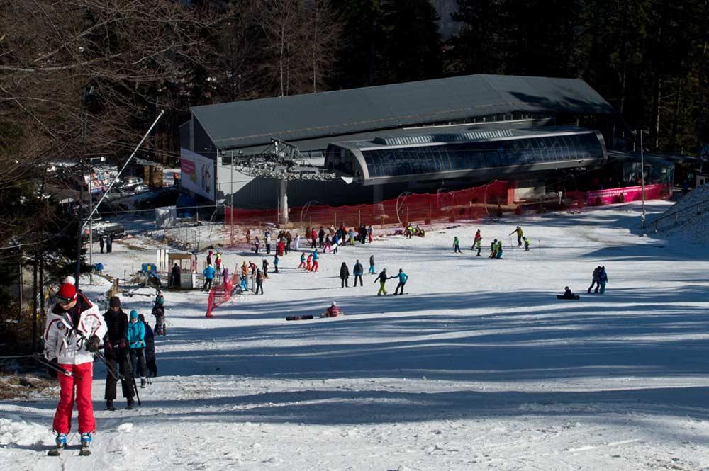 Skifahrer am Schlepplift mit Talstation im Hintergrund